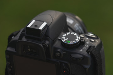 Nikon D3100 DSLR Kamera von schräg hinten rechts oben vor einem grünen Bokeh Hintergrund.