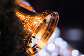 golden bells with a red bow on Christmas tree blur bright bokeh background