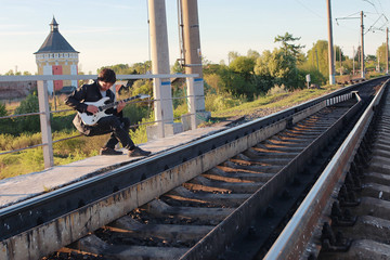 Naklejka premium Man with an electric guitar in the industrial landscape outdoors