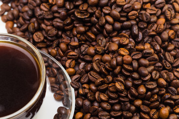 Black coffee in a glass cup and grains of coffee on a white background