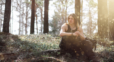 A musician with a tool in nature. A man is playing a flute in a pine forest. The music of the druids in the spring forest. © alexkich