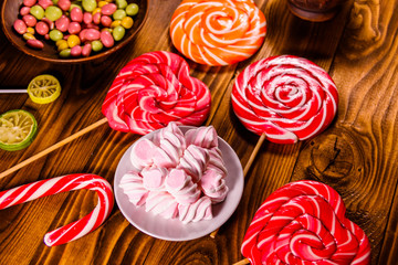 Ceramic plate with marshmallow, candy cane and lollipops on a wooden table