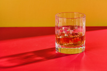 glass of whiskey on red and yellow background solo midlevel view background
