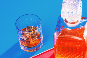 whiskey glass with decanter horizontal on blue and red focus on glass