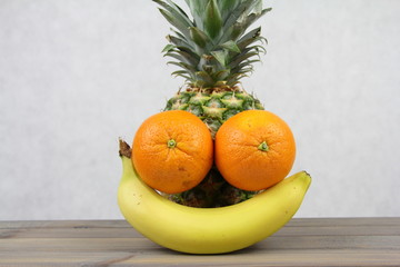 Zdrowe owoce - zadowolona mina - ananas, pomarańcze i banan na jasnym tle