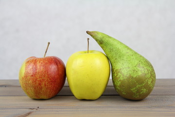 Owocowa dekoracja - czerwone i żółte jabłko z zieloną gruszką na jasnym tle