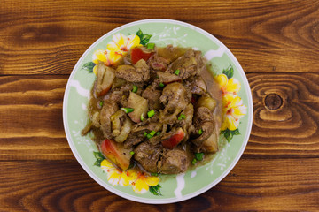 Stewed chicken liver with apple and onion on wooden table