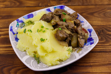 Mashed potatoes with stewed chicken liver with apple and onion on wooden table