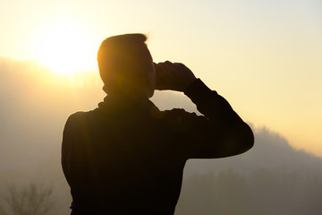 silhouette of a young man drinking beer out of can