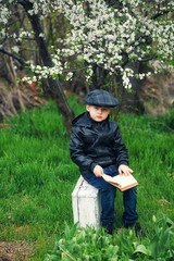 Naklejka na ściany i meble portrait of a boy in a spring blooming garden