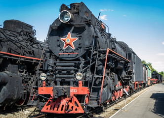 Old steam locomotive beside a railway station platform. Retro train.