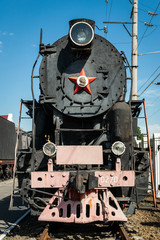 Old steam locomotive beside a railway station platform. Retro train.