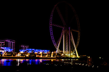 Dubai, UAE - November 19, 2018: Jumeirah Beach Residence JBR and the Dubai Ferris Wheel with night illumination.