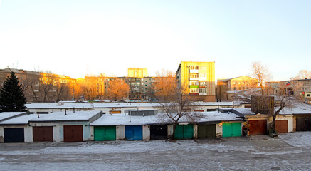 Ordinary Russian apartment buildings and garages for cars. The golden hour, before sunset.