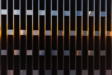 Abstract architectural detail of vertical lines with squares of metal at sunset.
