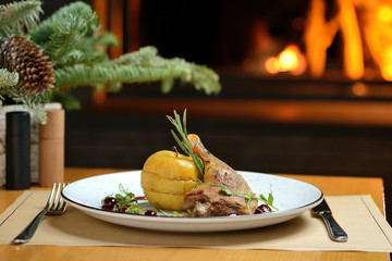 roasted chicken leg with apple and rosemary, against the background of the Christmas tree and fireplace