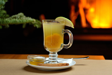 berry tea with lemon in a transparent glass on the background of the fireplace, Christmas tea