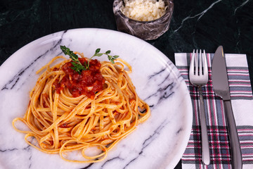 Delicious spaghetti served with parmesan cheese on a marble plate