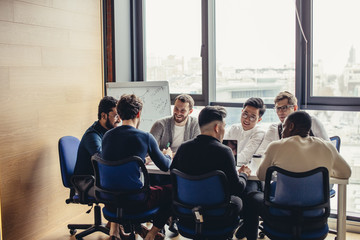 Weekly Meeting of all our sales division multiracial staff in the conference room. Group of business people having discussion in boardroom. Creative business team brainstorming over new project.