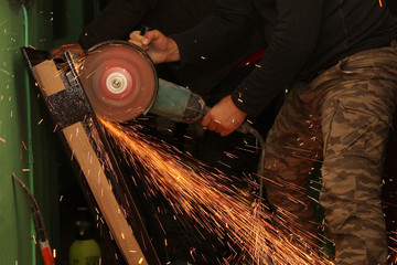 Worker cuts metal with a grinding machine in the process of many sparks