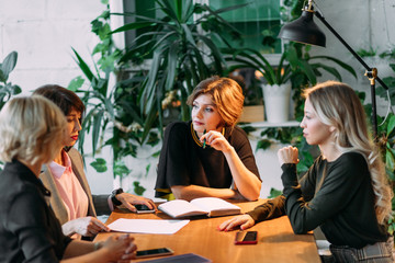 Group of younghardworking european young women working late at night in meeting room trying to...