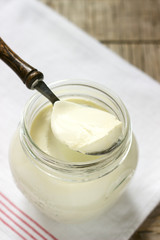 Homemade yogurt in a jar and spoon on a wooden background. Rustic style.