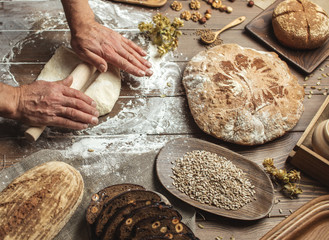 Male hands roll out dough on kitchen floured surface background with cooking background, close up. Cooking process concept.