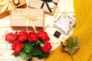 autumn and holiday concept: roses bouquet of flowers and boxes present, woolen scarf, algerian jam...