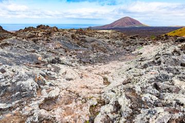 Vulcanic landscape with lava field and tourist road trail to vulcano Caldera Blanca, Lanzarote, Canary Islands, Spain.