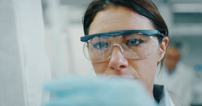 Portrait of female scientist with a pipette analyzes a liquid to extract the DNA and molecules in the test tubes in laboratory. Shot in 8K. Concept: research,biochemistry, pharmaceutical medicine