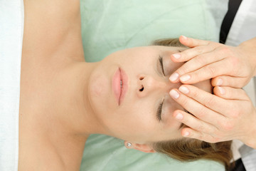 Naklejka premium Young woman getting spa massage treatment at beauty spa salon. Cosmetologist making girl relaxing Face and head massage. Spa skin and body care. Facial beauty treatment.Cosmetology.