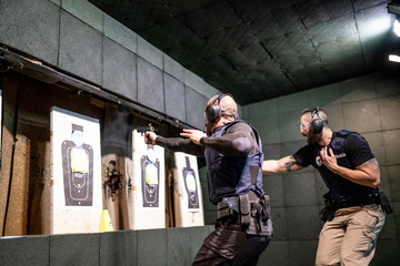 Police training in shooting gallery with short weapon. - obrazy, fototapety, plakaty
