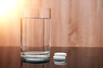 Anesthetic tablet, vitamins, in a glass of water with bubbles on a black table. Copy-space.