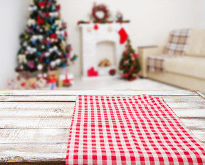 Fototapeta na wymiar checkered red tablecloth on wooden table on blurred holiday interior, new year and christmas concept, tablecloths