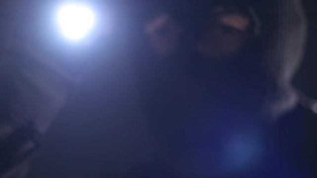 Burglar intruder with flashlight torch at night, low key selective focus in slow motion