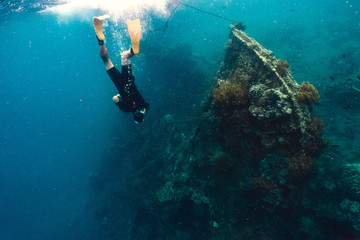 Fototapeta na wymiar Freediver and coral reef with fish near wreckship