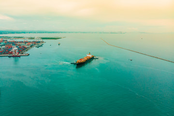 Container cargo ship and transportation, Business International trade and Container logistics export-import harbor to the International port / Cargo ship passing the harbor - Top view from drone