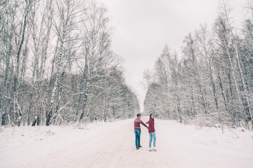 Teenagers in Christmas sweaters walking in snow in winter
