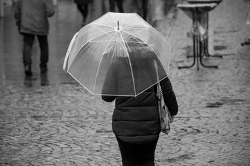 portrait of woman walking with transparent umbrella in the pedestrian street