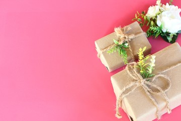 Gift box wrapped in recycled paper on pink background