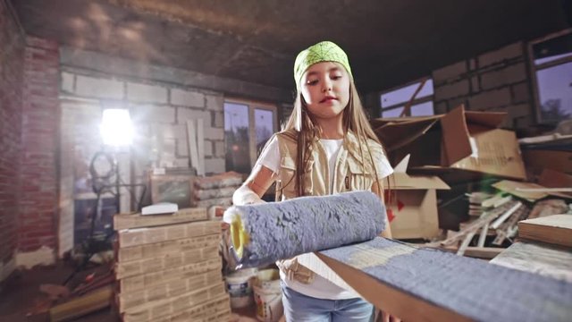Teenage girl coloring wood plank with roller