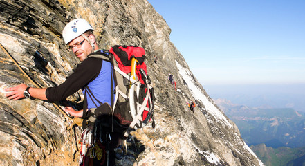 male mountain climber on a steep rock face on his way to the famous Eiger mountain in the Swiss...