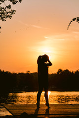 silhouette of young woman on the lake at sunset