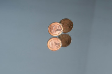 coins of one Euro and fifty cents on the edge with reflection
