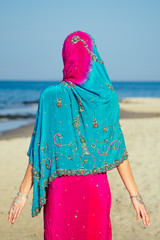 Young women wearing a pink blue saree on the beach goa India.girl in traditional indian sari on the shore of a paradise island among the rocks and sand enjoying the freedom and the morning
