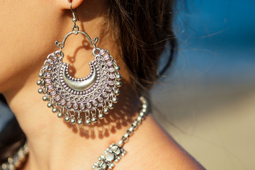 female model earrings and necklace in vacation on paradise tropical beach by ocean sea. hindu woman...