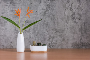 Flowers vase with Cactus pot on wooden table raw concrete background.