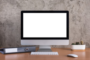 Blank screen of all in one computer with  document file and cactus vase on raw concrete background