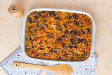 Casserole in a baking tray on a wooden table. The finished dish is baked in the oven.