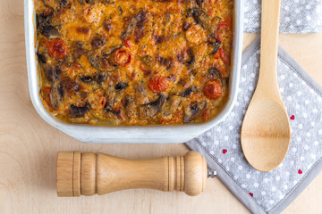 Casserole in a baking tray on a wooden table. The finished dish is baked in the oven.